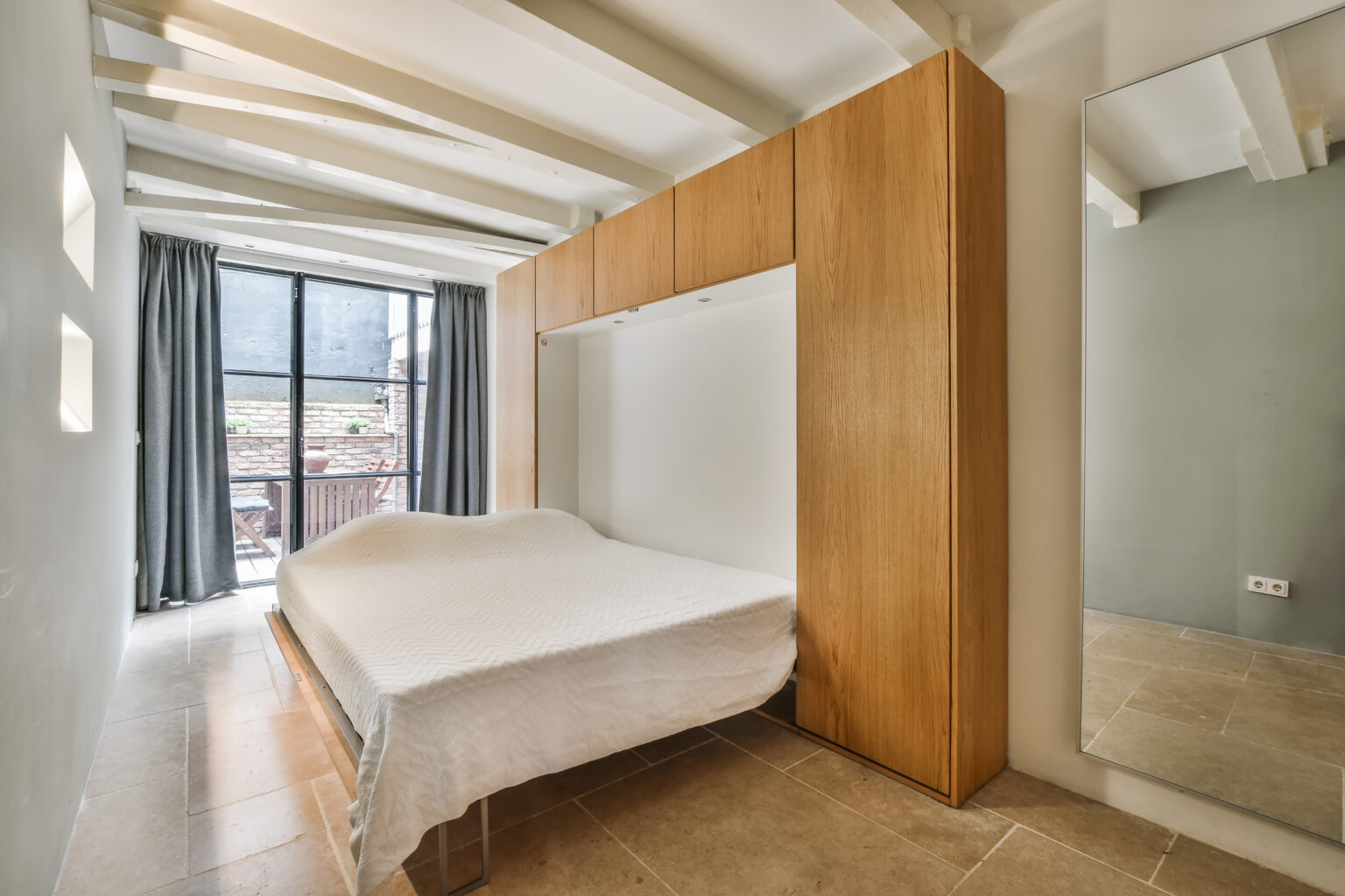 Custom Murphy bed mattress folded down from a modern built-in cabinet in a compact condo bedroom